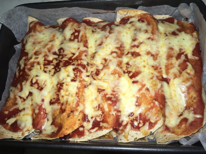 a roasting pan with five enchiladas in it, covered in tomato puree and melted cheese