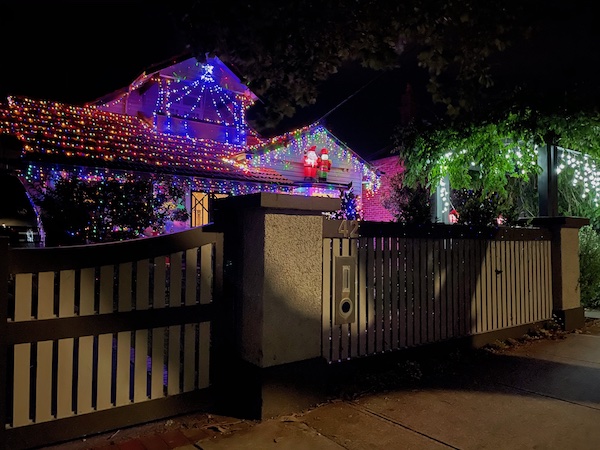 an older house with lights on the roof and tree