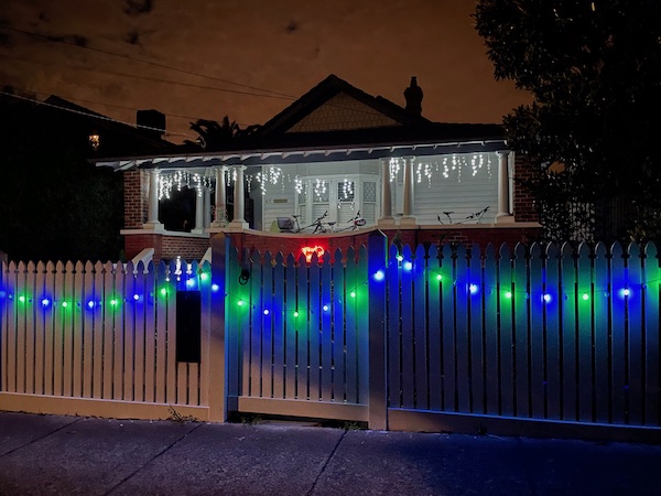 a house close to the street with bright snowflake lights and a 'Merry Christmas' light
