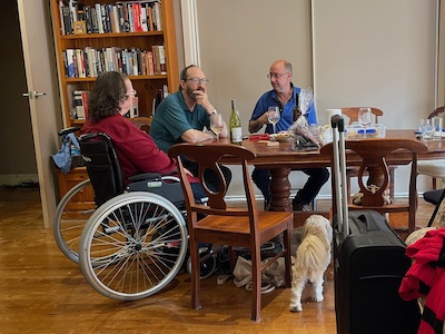 three middle-aged to older adults sitting around a dining table, chatting