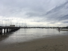 a view of calm ocean water, a pier to the left