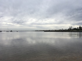 a view of calm ocean water, cloudy sky above