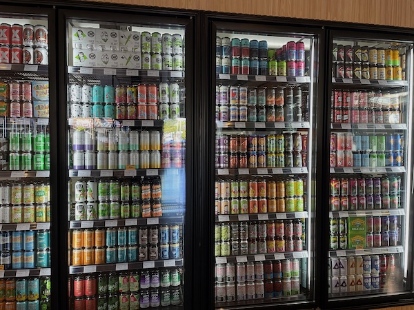 fridges at a bottle shop, displaying many colourful cans of beer