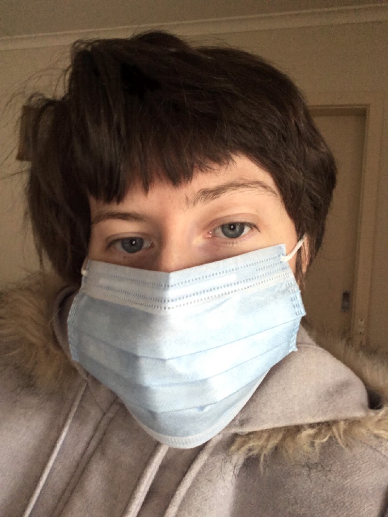 a selfie where I'm indoors in a disposable mask and light blue winter coat