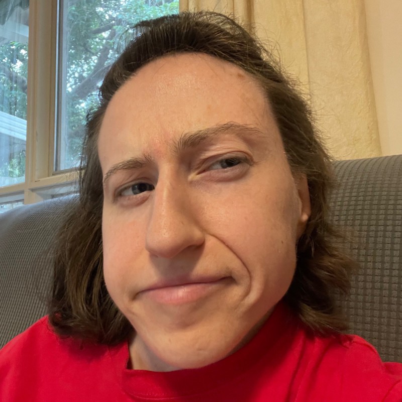 a photo of a young woman in a red t-shirt pulling an 'um what' kind of face