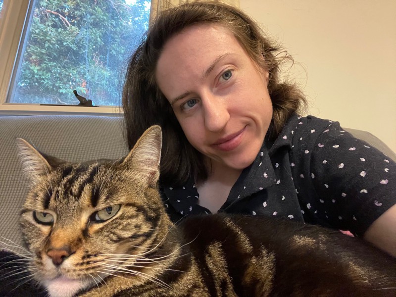 a young woman in patterned pyjamas and a tabby cat