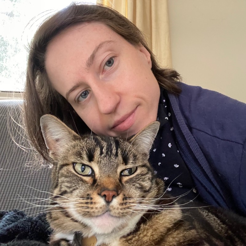 photo of a young woman in pyjamas with a tabby cat