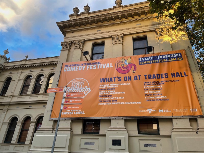 an exterior shot of Trades Hall, with a large MICF banner up listing all the shows they have at that venue