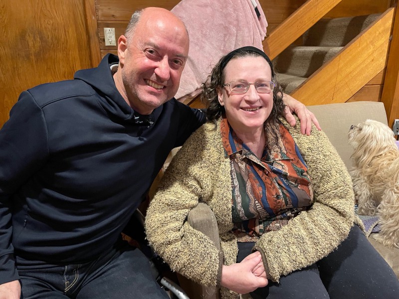 a man and a woman sit side-by-side, smiling at the camera