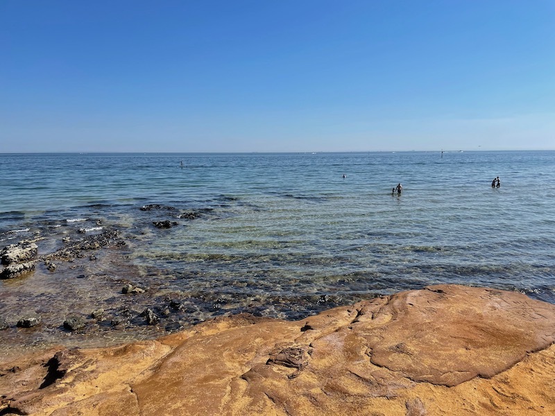 sand, shallow sea with some rocks, blue sky