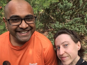 a selfie of a man and woman standing in front of some shrubbery, both smiling